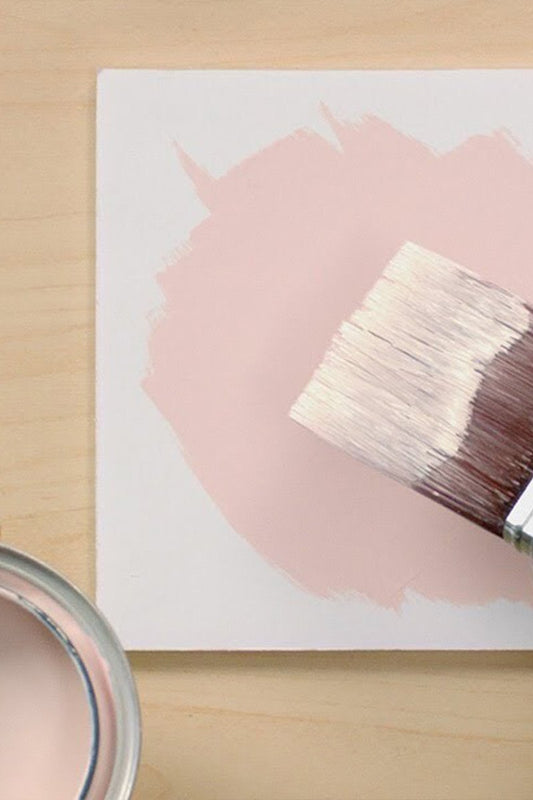 top down view of paint brush paint can and white block with pink circle painted on"