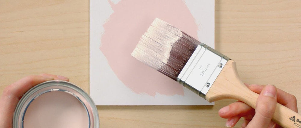 top down view of paint brush paint can and white block with pink circle painted on"